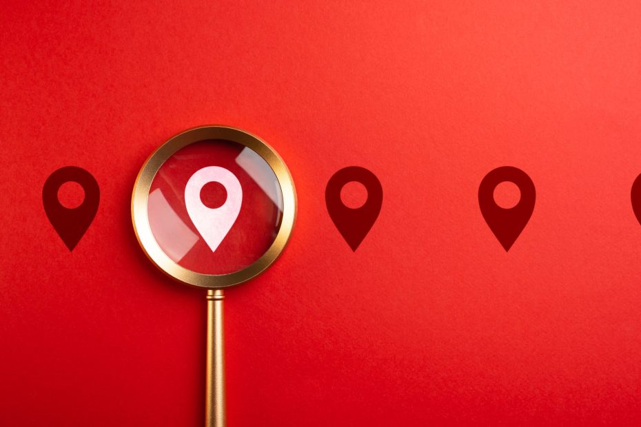 Roter Hintergrund und eine Lupe die auf das Standort Zeichen zeigt